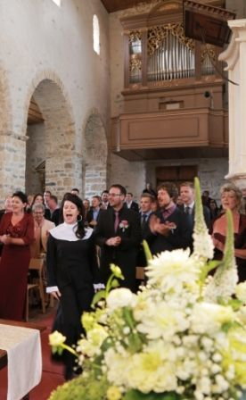 Kirche Spiez im Sister Act Kostüm singt die Sängerin zwischen den Gästen Amen........